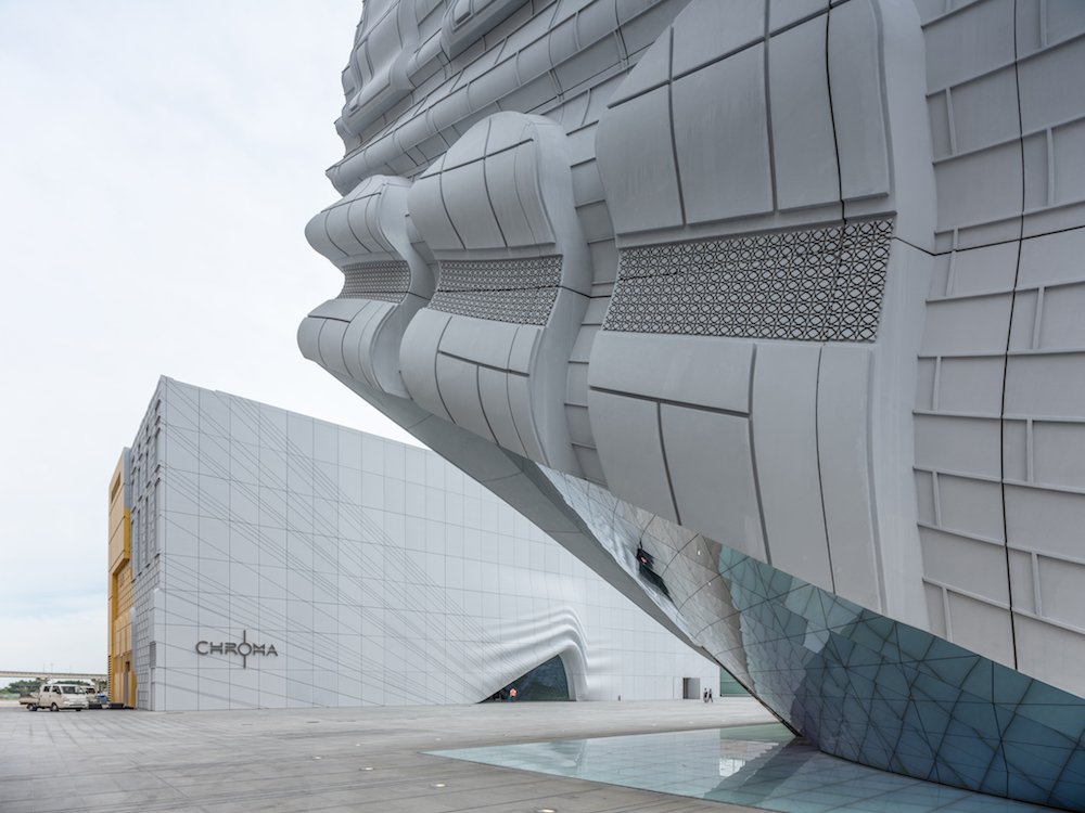 A grey building with a corner lifted up, revealing a mirrored underside